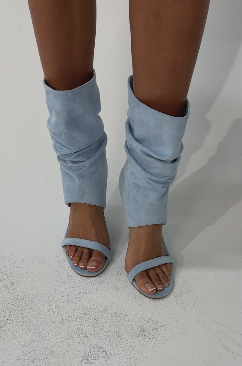 Video of woman modeling the AZALEA WANG KYVELISA BLUE WEDGE OPEN TOE BOOTIE, featuring light blue faux suede and a unique inverted wedge heel. Only their legs and feet are visible.