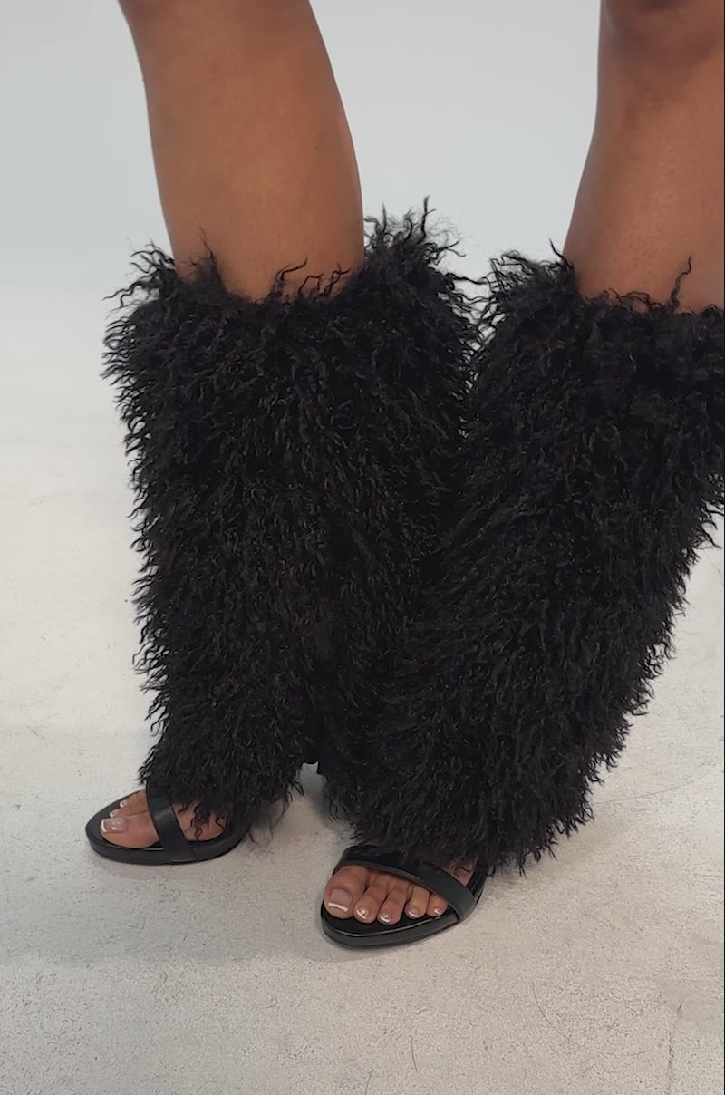 Video of woman modeling the AZALEA WANG CLOUD NINE BLACK FUR OPEN TOE BOOT with knee-high black shaggy faux fur, plus a black sequin skirt, this bold Y2K-inspired look stands out against a plain background.