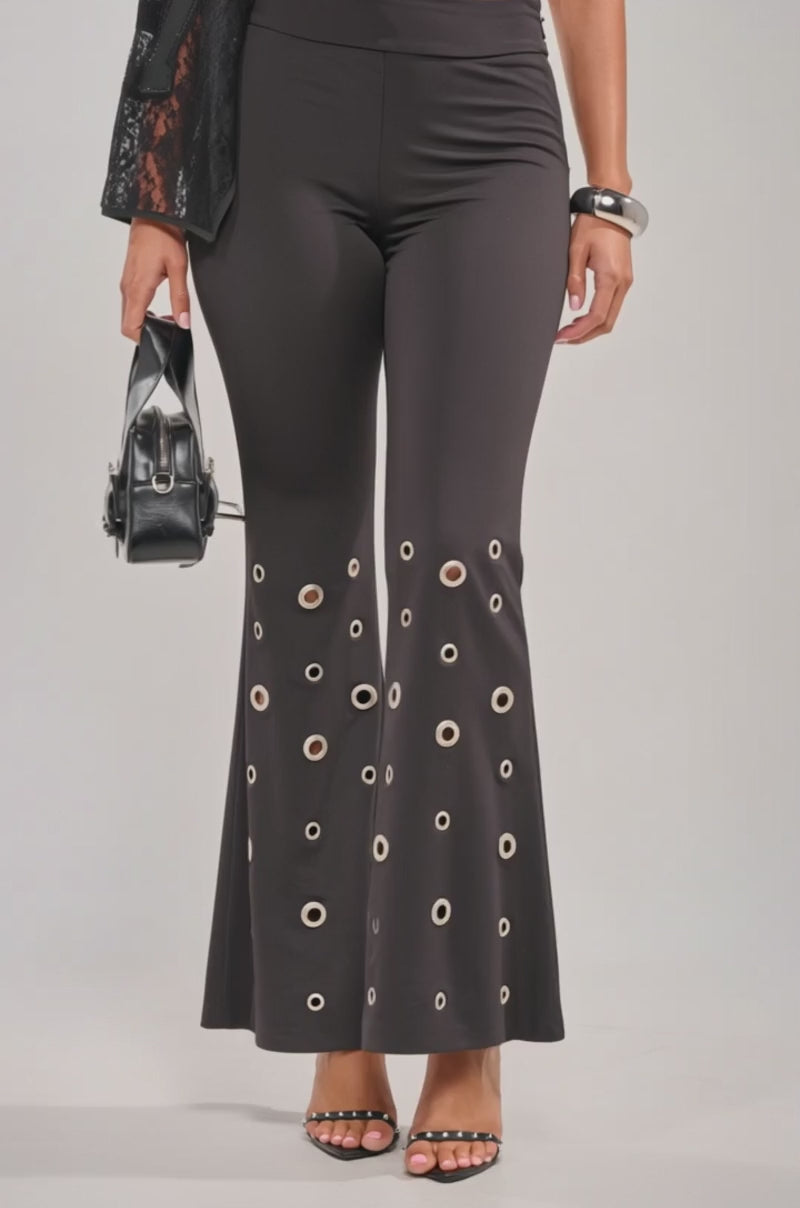 Video of woman modeling the CHECK IT OUT GROMMET FLARE LEGGING—black, high-rise with a silver grommet hem—styled with a small black bag, silver bangle, and open-toe heels.