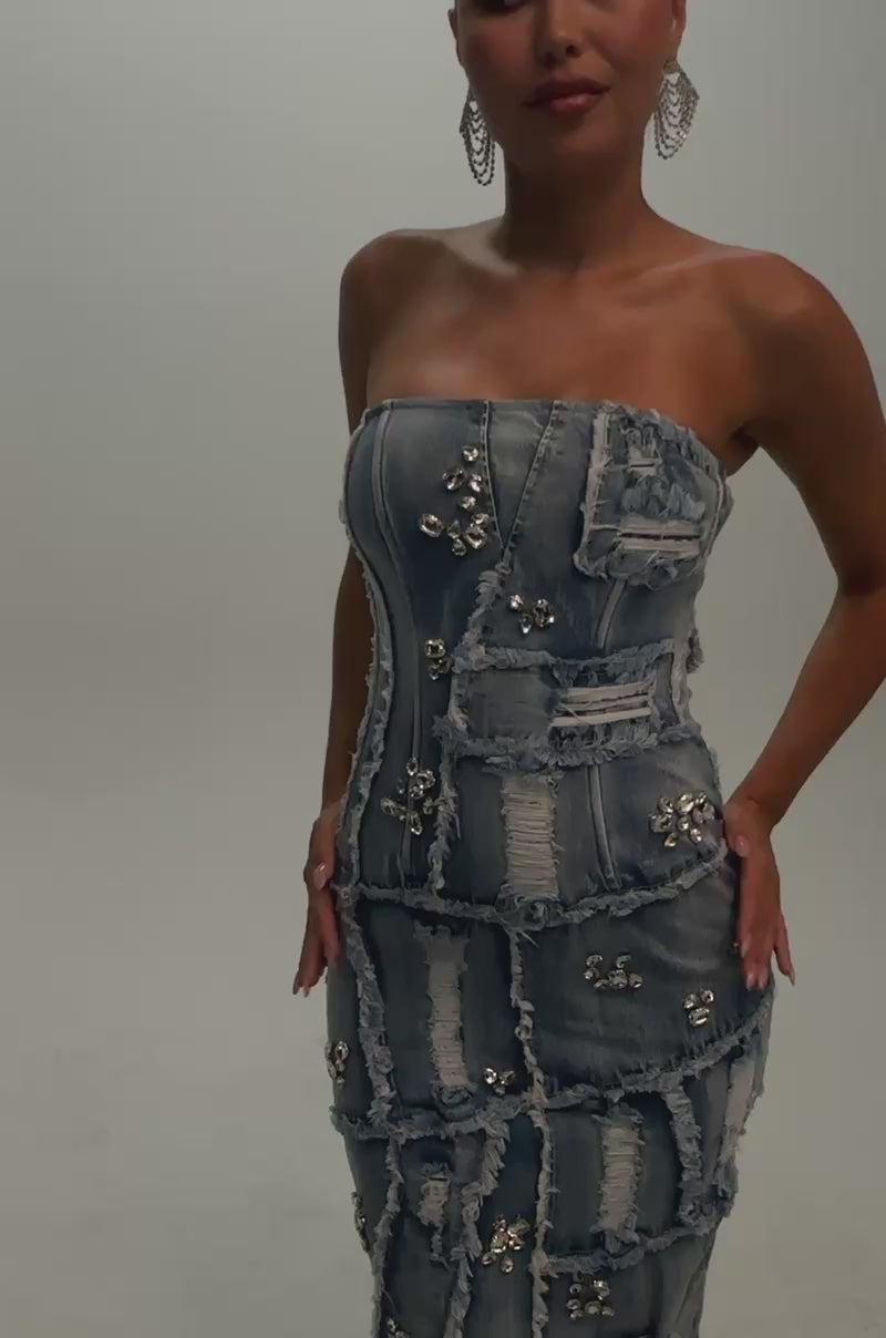Video of a woman modeling the LELANI DISTRESSED RHINESTONE DENIM MIDI DRESS—a strapless, body-hugging dress featuring distressed denim, patchwork details, and shimmering rhinestone embellishments.