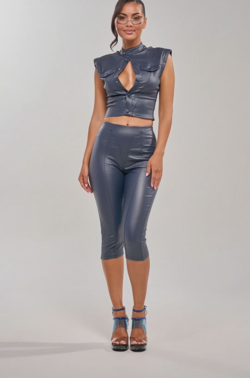Video of woman modeling the BIG CITY LIVIN FAUX LEATHER CAPRI, a navy high-waisted faux leather capri pant. She pairs it with a fitted dark top, clear heels with blue straps and glasses