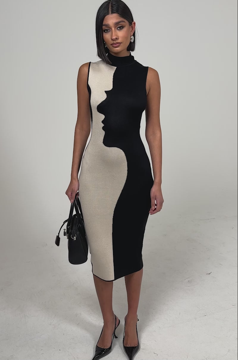 A video of a woman wearing the GEMINI MIDI SWEATER DRESS in black and beige, featuring a graphic face profile. 