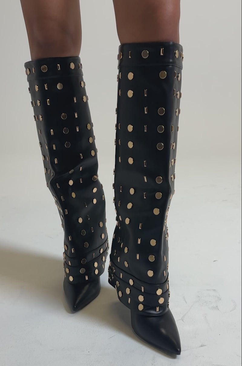 A video of a person wearing the AZALEA WANG ANISSA Black Multi Gold Hardware Stiletto Boot with black faux leather shorts.