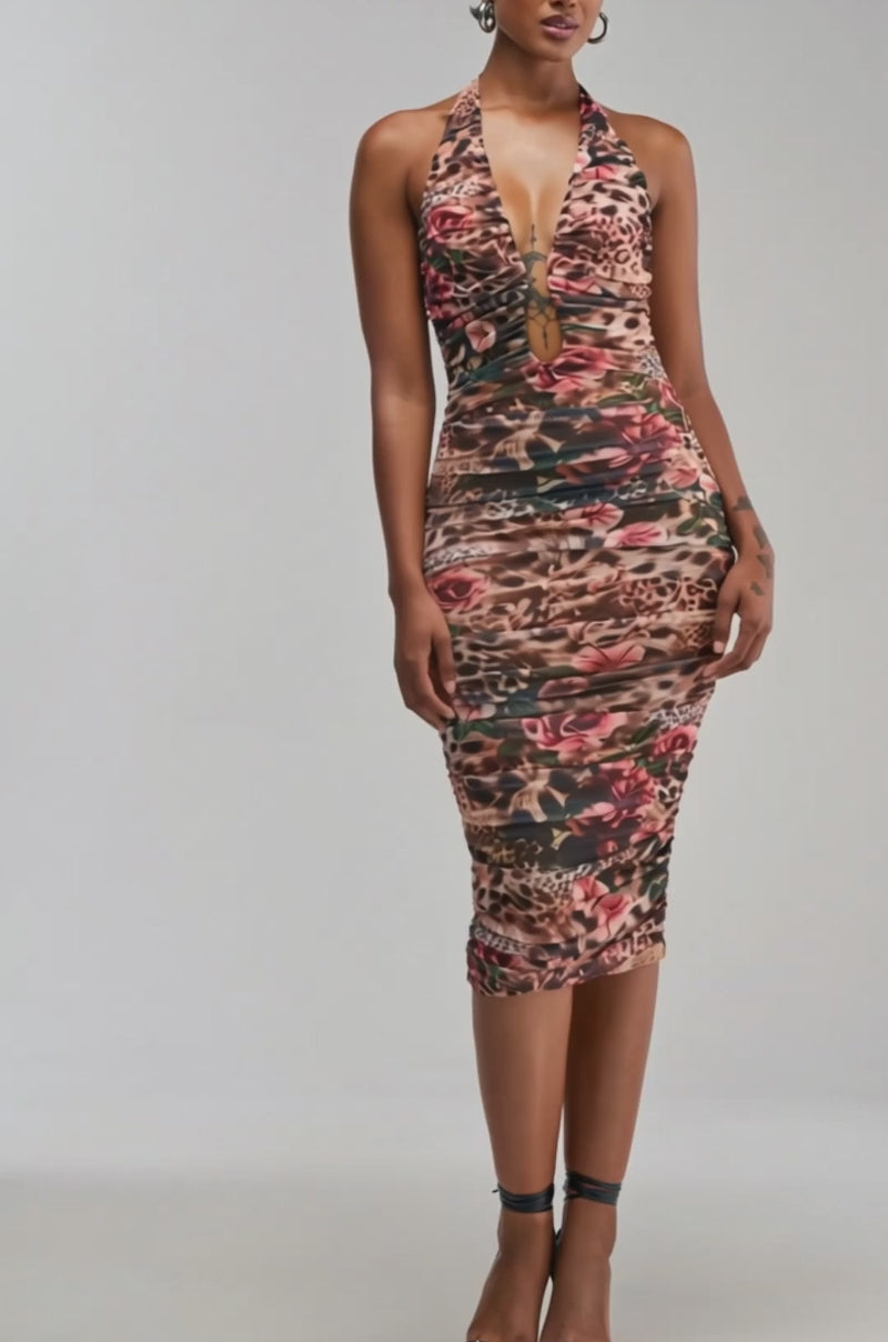 Video of a woman modeling the CLOUD NINE PRINTED MAXI DRESS IN BROWN CHEETAH, a woman poses in a fitted, sleeveless halter style featuring a deep V neckline and ruched detailing. The dress showcases an eye-catching brown cheetah print. 