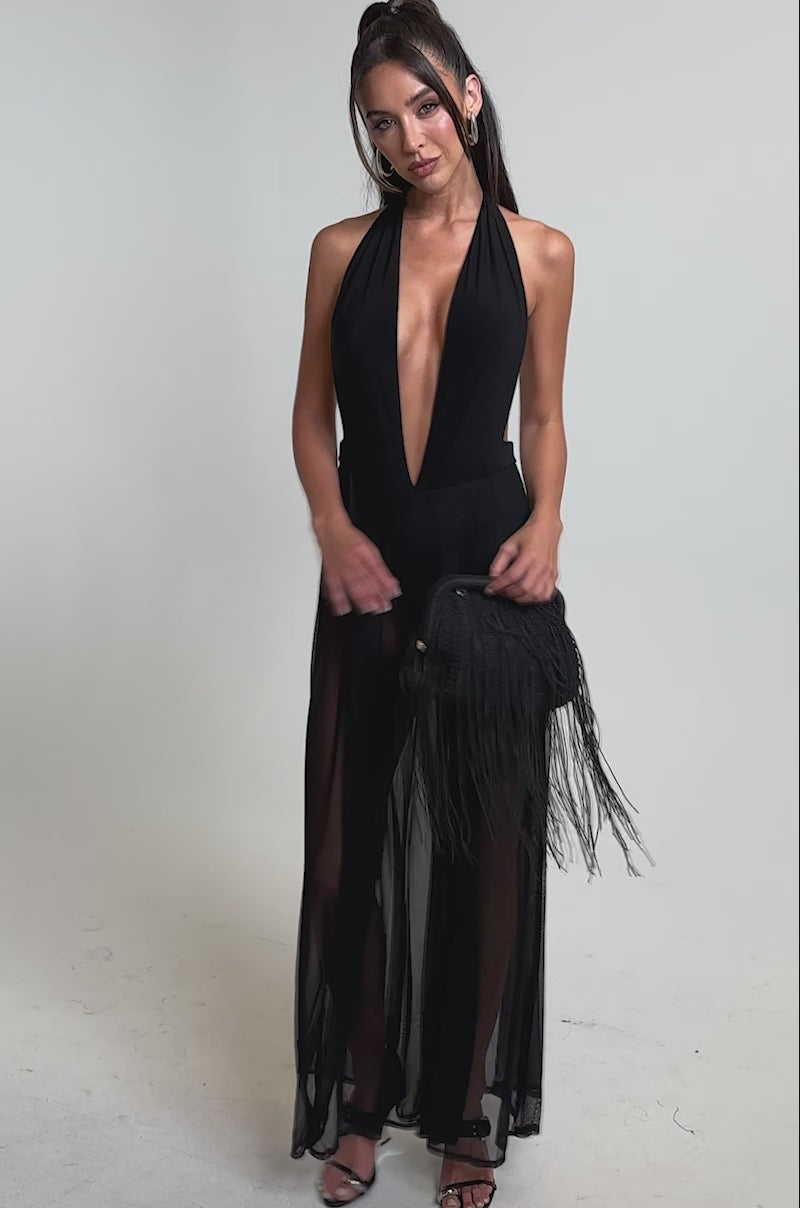 A video of a woman in the BOMBSHELL MESH JUMPSUIT, featuring a black halter-neck, open back, and deep V-neckline.