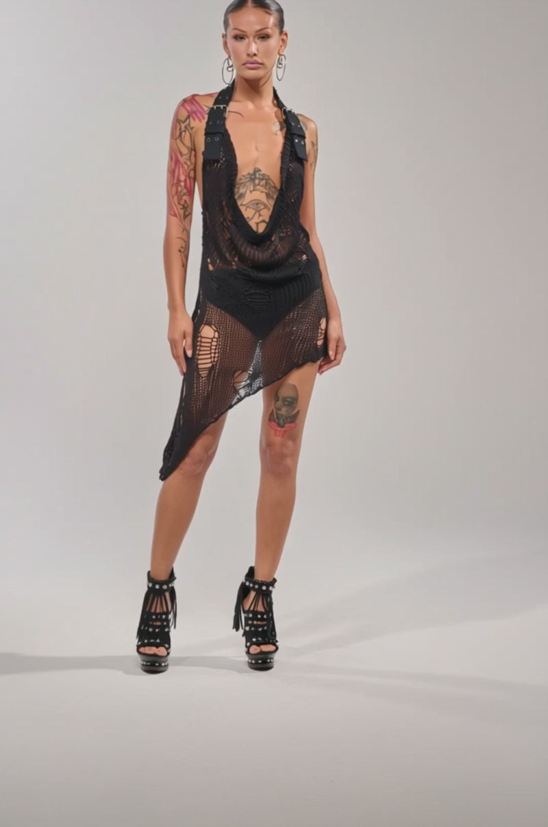 A video of a model in the MAKE A MESS KNIT MINI DRESS IN BLACK and strappy fringe high-heeled sandals.