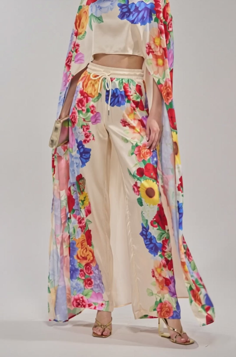 Video of woman modeling the FLORAL BURST CAPE TOP, an off-white satin cape with flowers