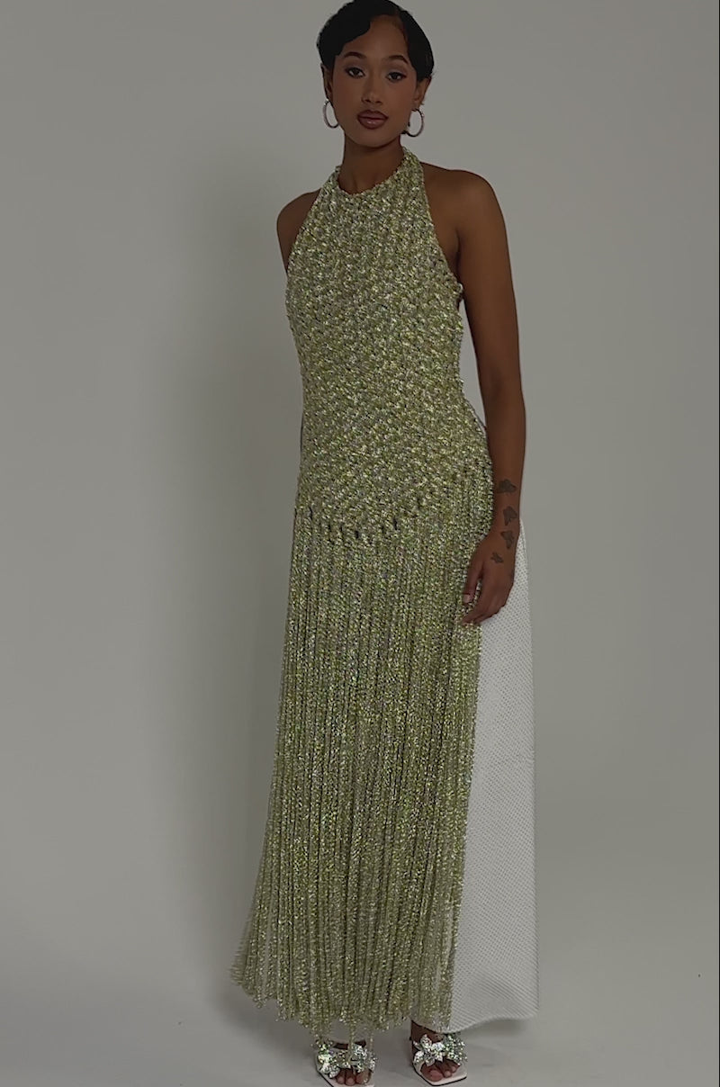 Video of woman modeling the ON SOME FRINGE BLOUSE, a sleeveless gold top with long fringe details, paired with wide-legged white pants, hoop earrings, and silver heels—an ideal party look set against a plain light background.