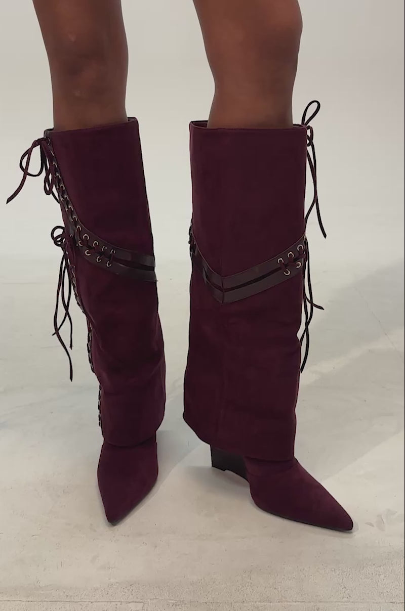Video of woman modeling the AZALEA WANG Magenta Plum Faux Suede Wedge Boot, featuring a knee-high design with pointed toes, lace-up details, and grommet accents.