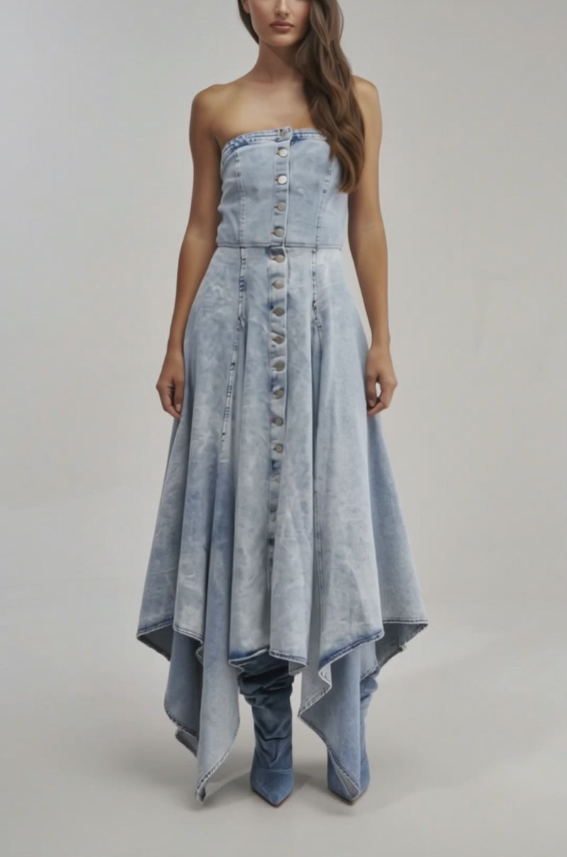 A video of a woman wearing the MISS ME YET STRAPLESS DENIM MIDI DRESS with a handkerchief hem and silver button front, styled with matching denim boots against a plain light backdrop.
