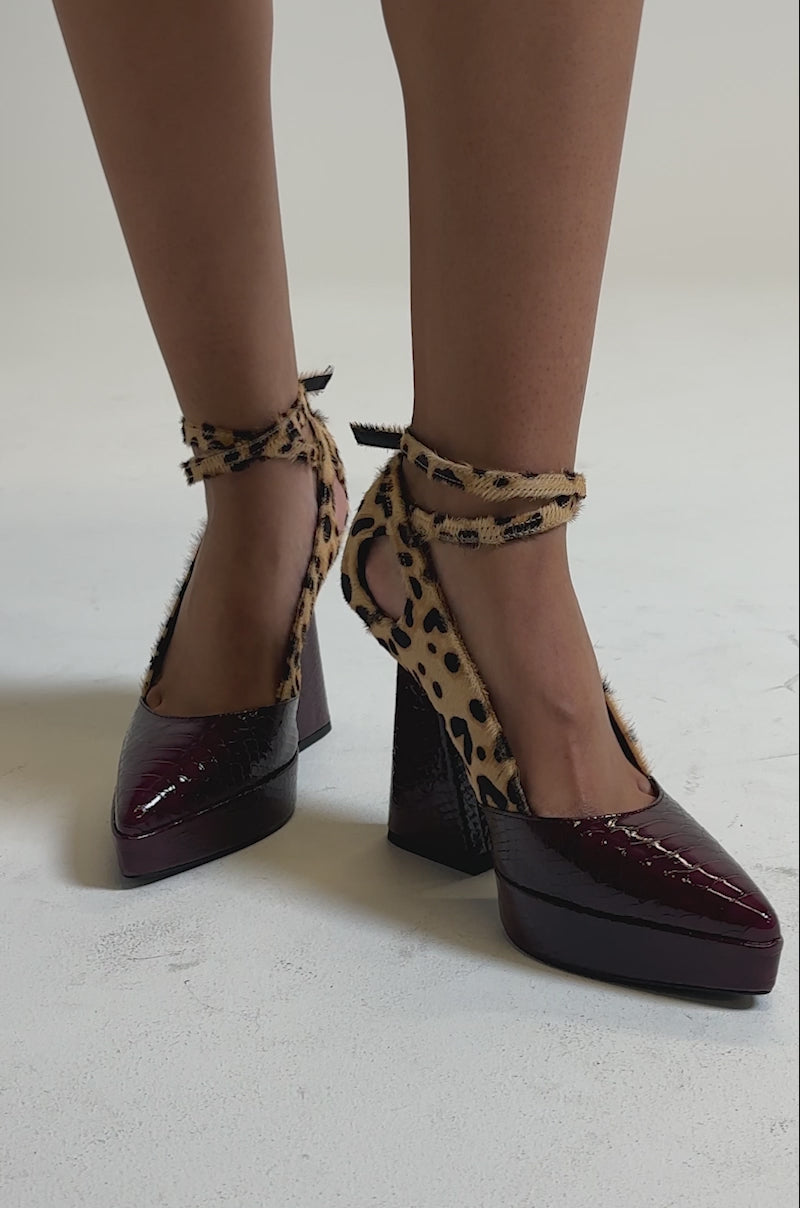 A video of the AZALEA WANG VEVELYN MULTI CHUNKY PUMP, they are shoes with burgundy, crocodile-textured toes, platform heels, and leopard-print ankle-wrap straps.