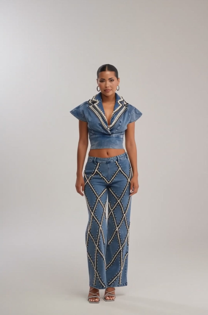 Video of woman modeling the DRIPPING IN PEARLS DENIM BLOUSE, a high-collared, short-sleeve denim top adorned with pearl crisscross patterns, paired with matching flared jeans for a chic streetwear look.
