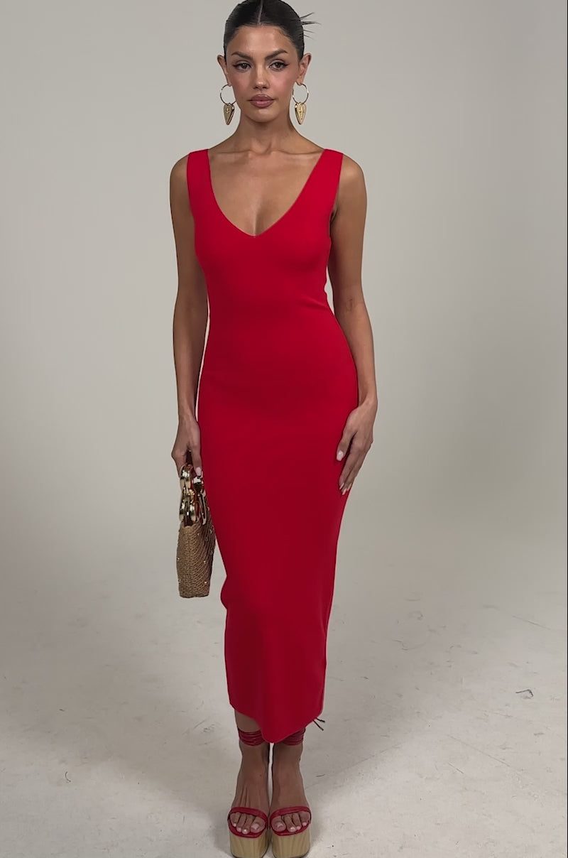 Video of woman modeling the BETWEEN THE LINES MIDI DRESS IN RED with platform sandals, a woven handbag, slicked-back hair, and large hoop earrings.