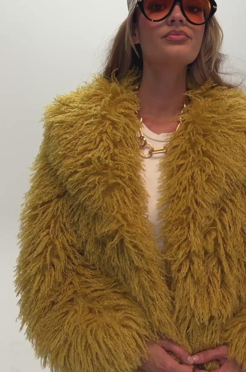 Video of a woman modeling the CHIQUITA FAUX FUR jacket in mustard yellow.