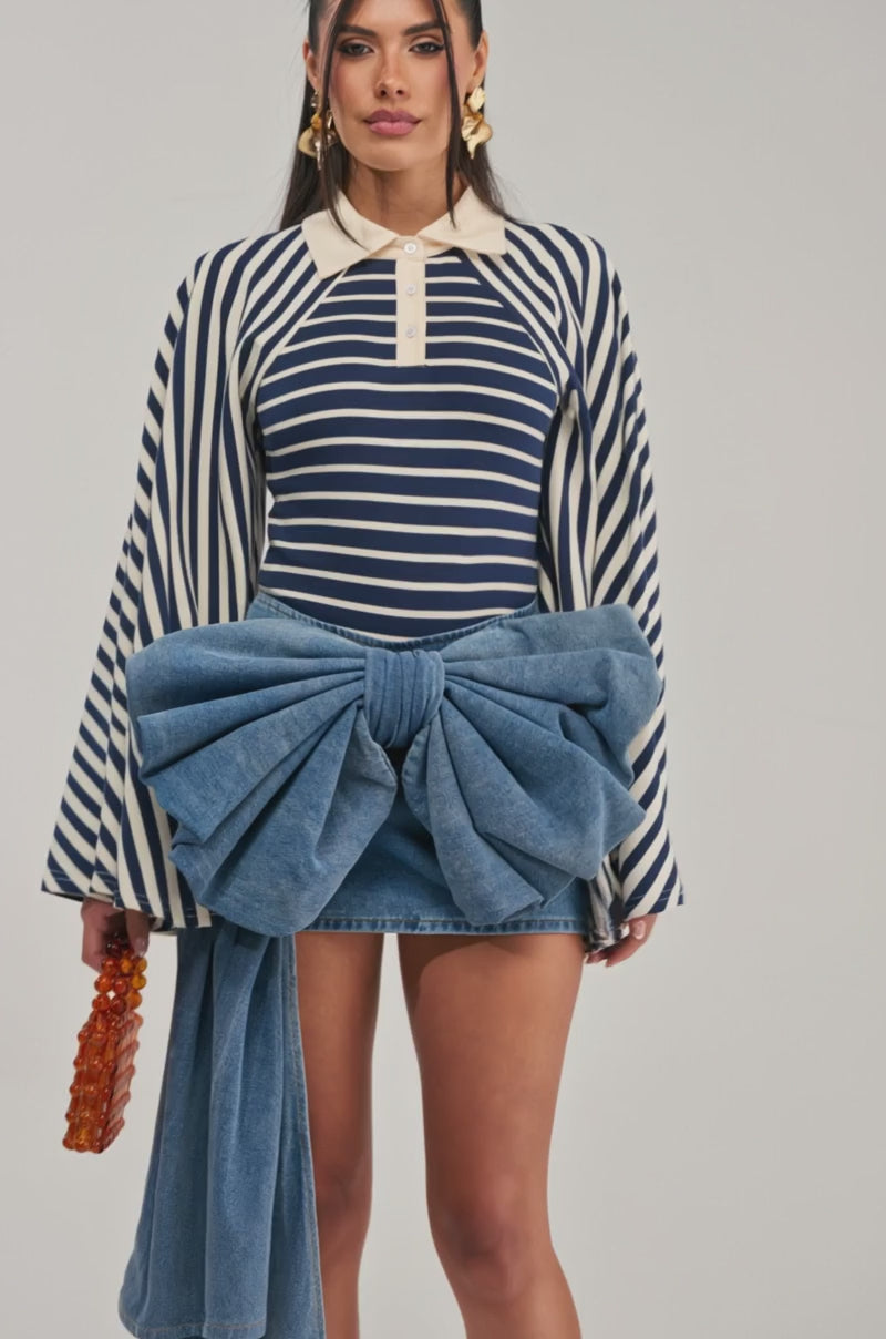 Video of a woman modeling the EXTRA IS GOOD MINI SKIRT WITH BOW—a Y2K-inspired oversized denim mini skirt featuring a statement bow.