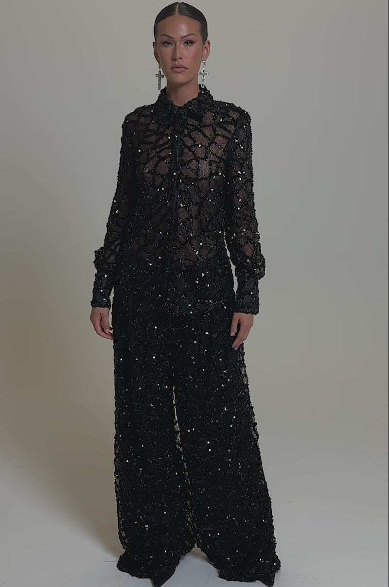 A video of a woman in the ROXY SEQUIN BUTTON DOWN paired with high-waisted, wide-leg black sequin pants. 