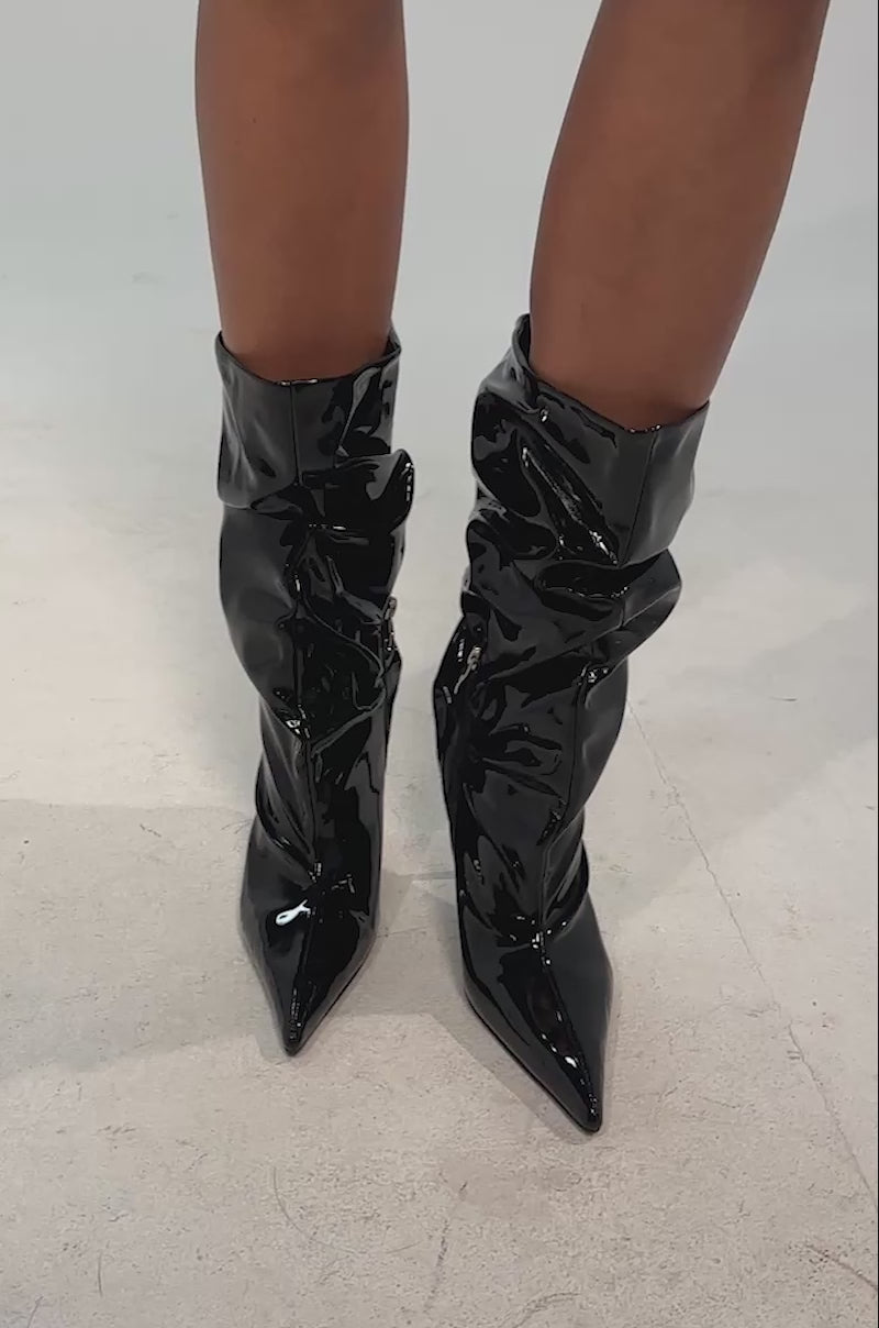 Video of woman modeling the AZALEA WANG MISTRA BLACK PATENT SLOUCHY STILETTO BOOT, featuring pointed toes and mid-calf slouchy design, shown on a neutral background.