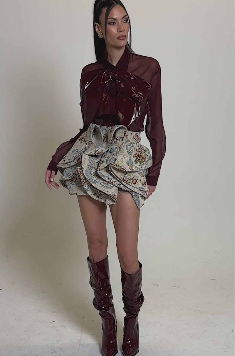 Video of woman modeling the  FLORAL BABY RUFFLE SKIRT, which features short ruffles and blue, beige, and red floral tapestry patterns.