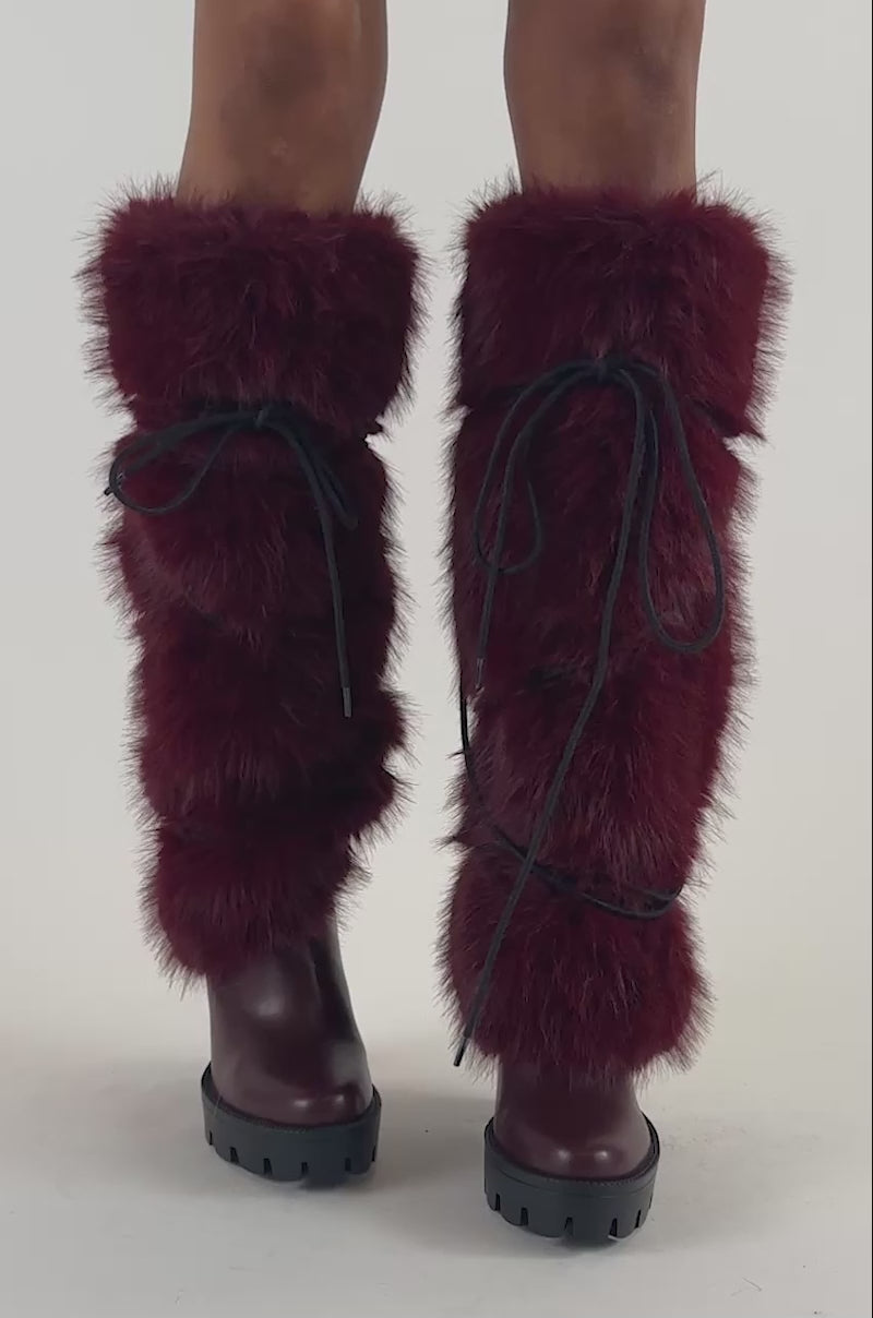 Video of a woman modeling the AZALEA WANG CYRENE BURGUNDY FUR BLOCK HEEL BOOT with striking knee-high burgundy faux fur and black laces.