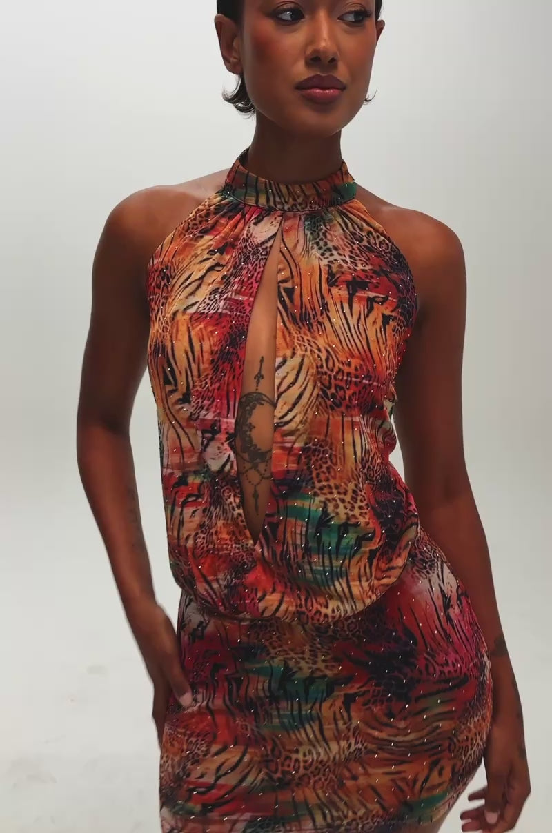 Video of a woman modeling the Fashionista Rhinestone Mini Dress in Red Multi—a sleeveless mini dress featuring a multicolored animal print and a front keyhole cutout.