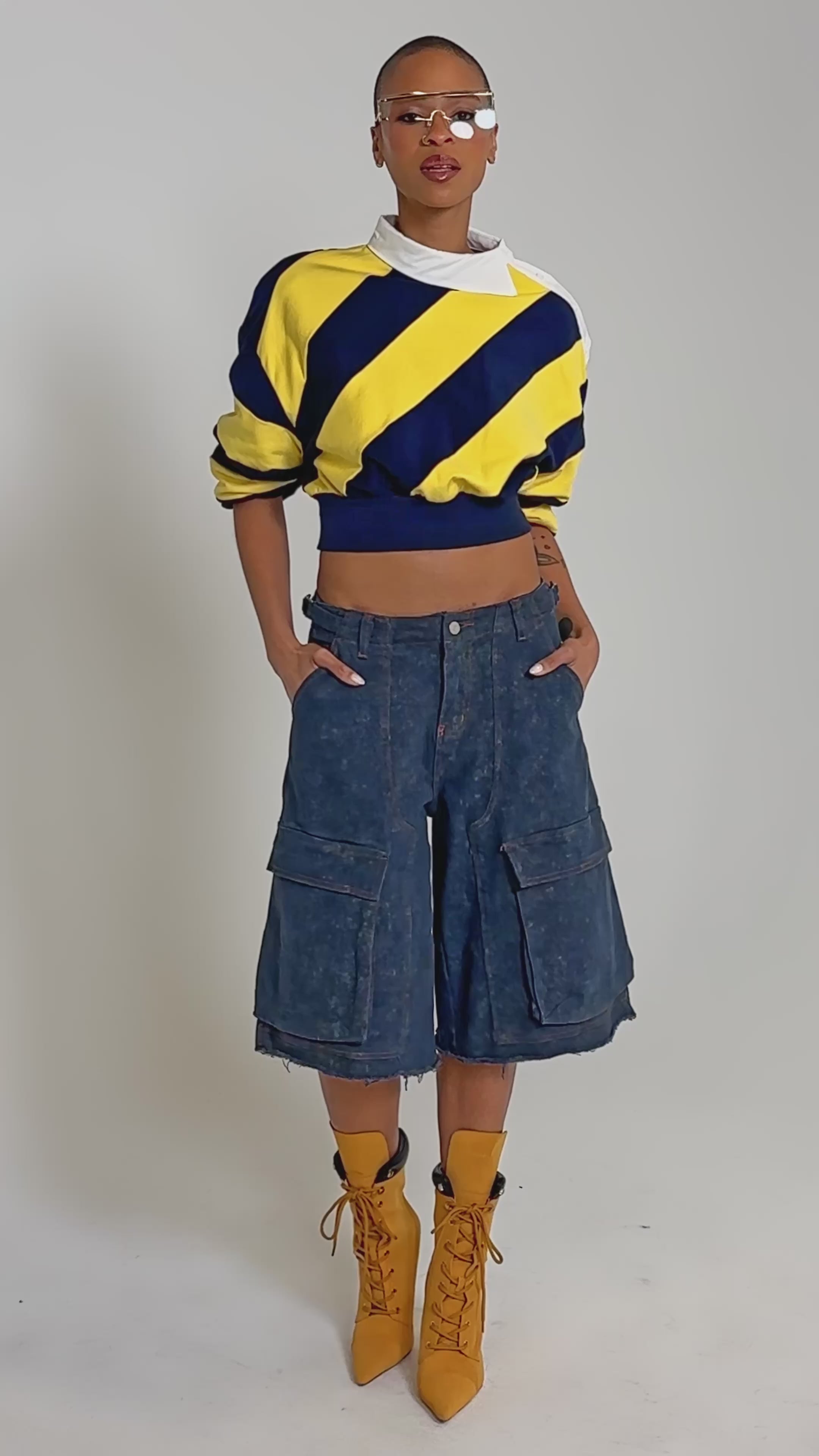 Video of woman modeling the JULIANA STRIPE SWEATSHIRT IN YELLOW, clear geometric glasses, and high-waisted denim jeans