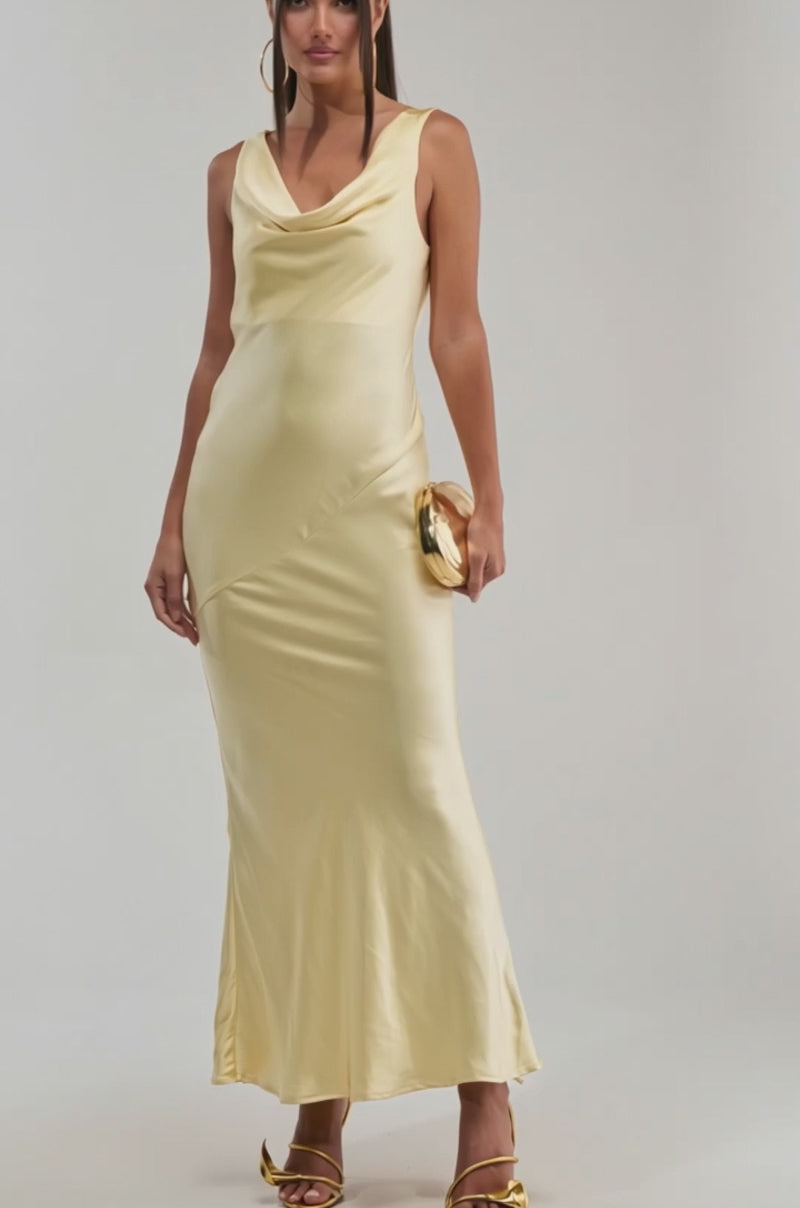 A video of a woman in the SOFT LAUNCH SATIN MAXI DRESS IN BUTTER YELLOW, featuring a cowl neck and maxi silhouette.