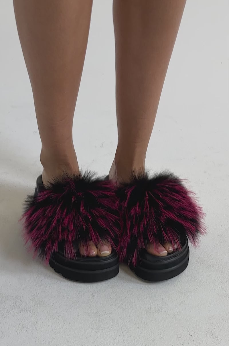 A video of a person wearing the AKIRA MIRAY PINK MULTI FUR SLIDE—black faux leather platform sandals with spiky pink faux fur.