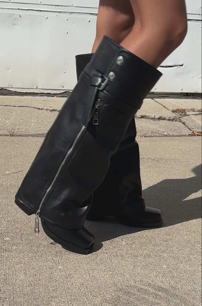 A video of a model wearing AZALEA WANG EIRA Chunky Bootie with Square Toe and a red textured coat, a person stands on the sidewalk, their upper thigh tattoo visible.