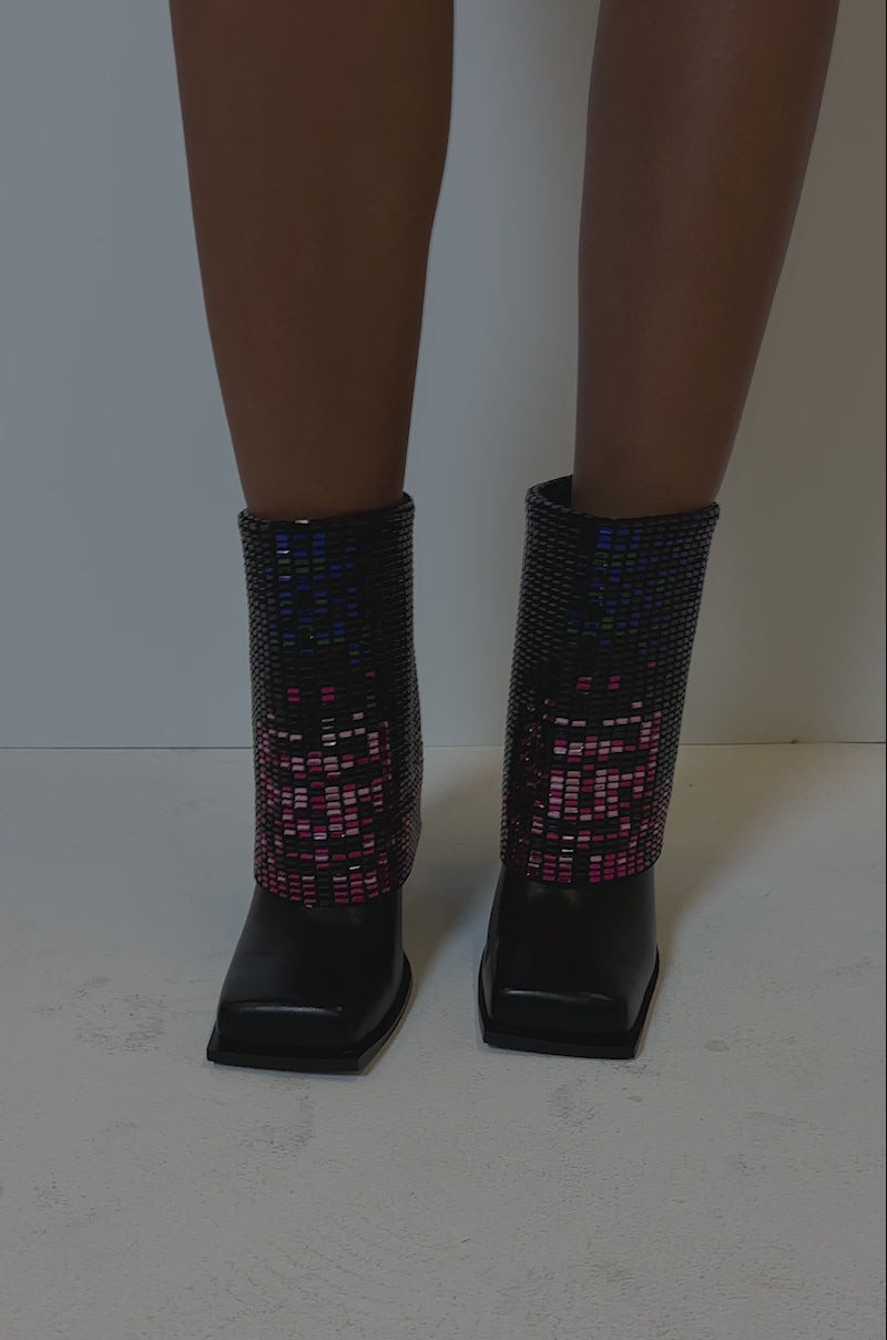 Video of person modeling the AZALEA WANG VOLLMER BLACK RHINESTONE CUFF BOOTIE WITH SQUARE TOE, adorned with blue, pink, and purple sequins. 