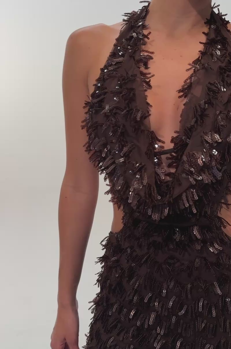 A video of a woman wearing the FIRST MOVE EMBELLISHED SEQUIN MINI DRESS IN BROWN, a sleeveless mini dress featuring a deep V-neck, textured fringe-like sequin detailing, and side cutouts. 
