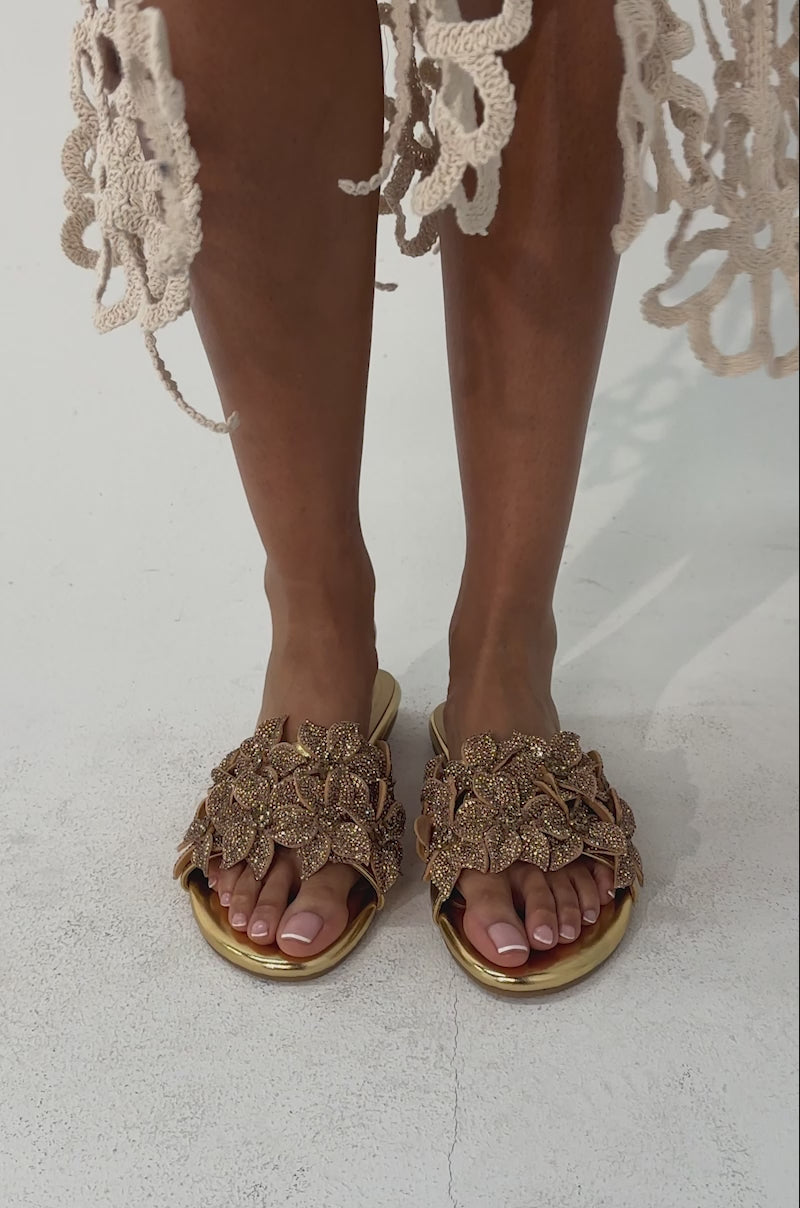 A video of a person wearing AZALEA WANG YUNA gold flat slip-on sandals embellished with rhinestones. 