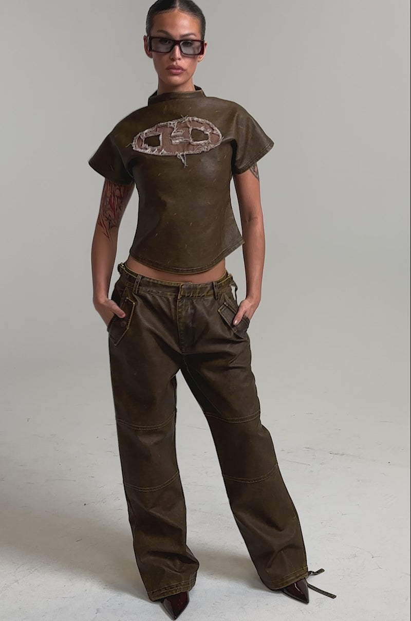 Video of woman modeling the ALL AROUND THE CITY MOCK NECK TOP—a vintage washed cropped brown shirt with a textured logo.