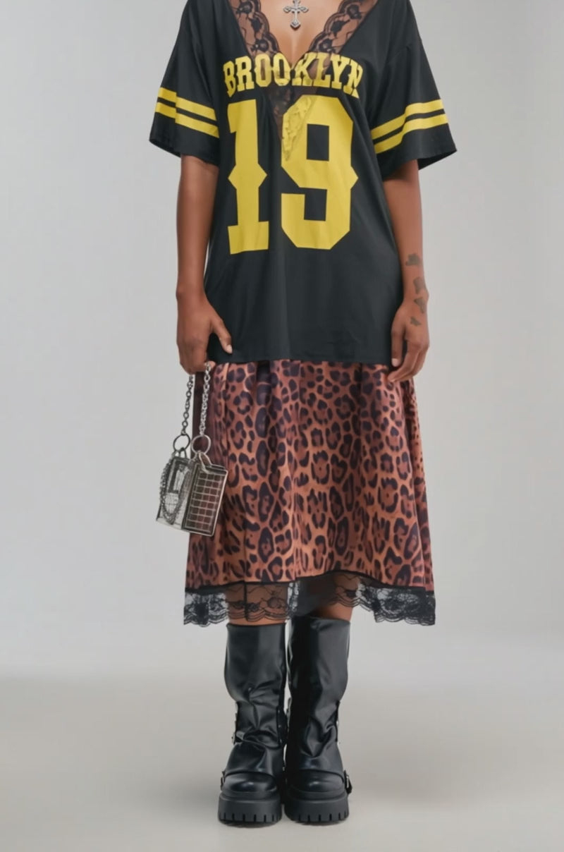 Video of a woman modeling the CITY GIRL LAYERED JERSEY MAXI DRESS, this look features a chic black “Brooklyn 19” sports shirt over a cheetah print maxi dress.