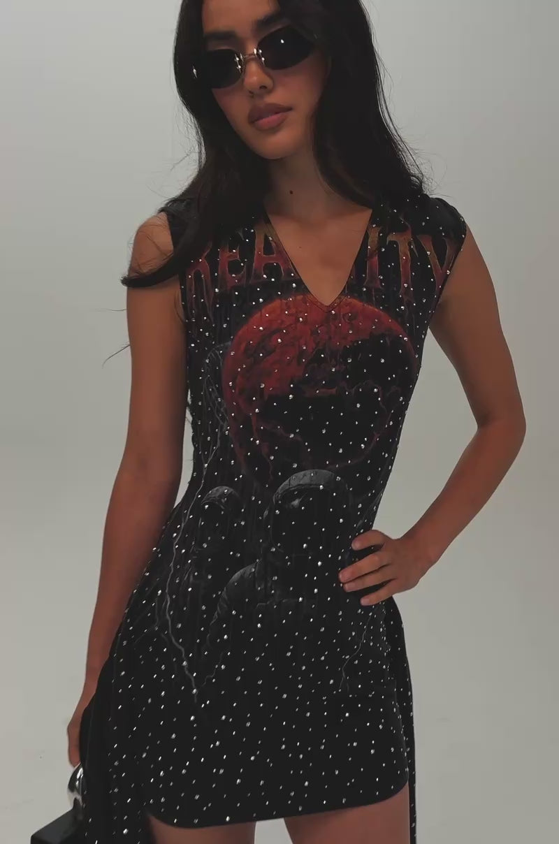 Video of a woman modeling the OUT OF THIS WORLD RHINESTONE MINI DRESS—a black, sleeveless mini dress adorned with a star pattern and a hood.