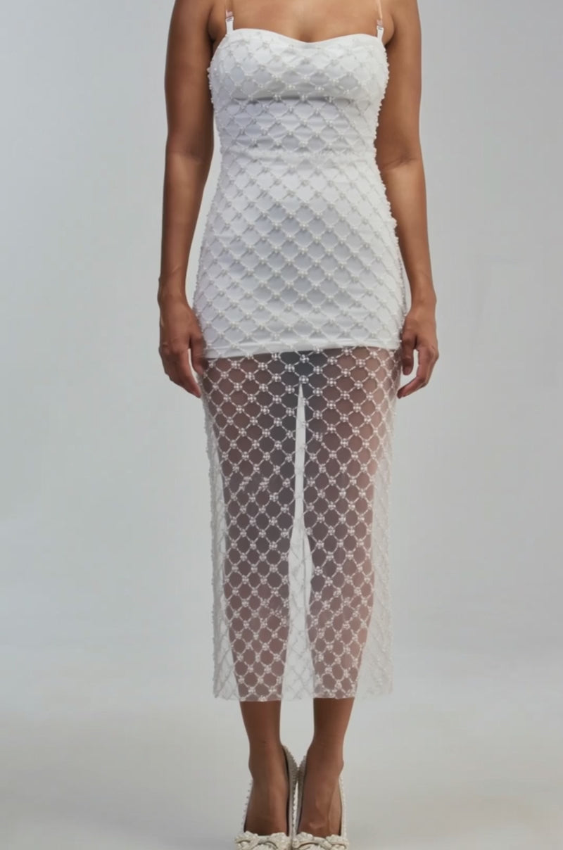 Video of a woman modeling the PARTY HARDER PEARL MINI DRESS IN WHITE. The fitted mini dress features spaghetti straps and a sheer mesh overlay extending below the knee.