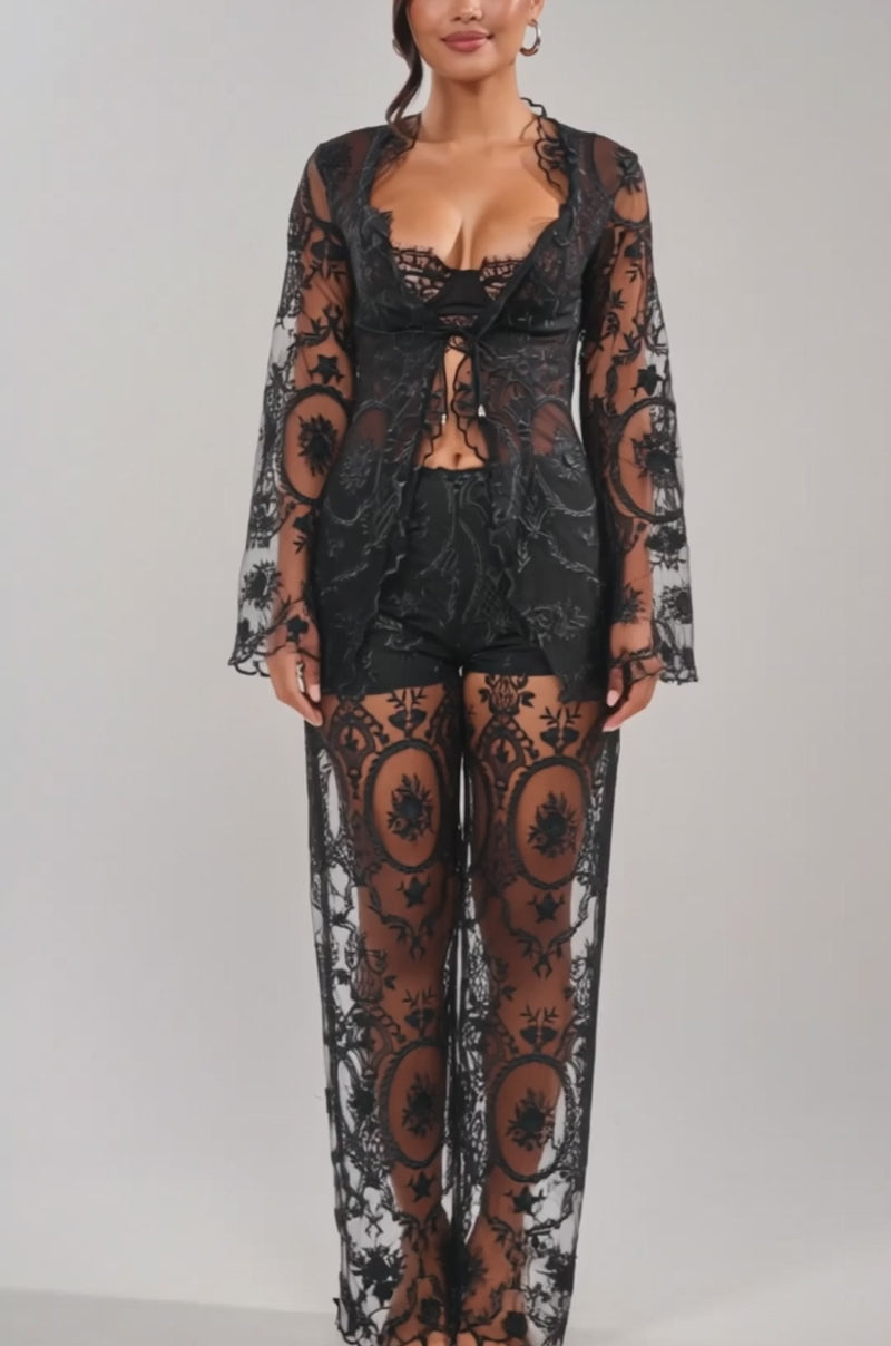 Video of woman modeling the SUPER LUXE LACE TIE-FRONT BLOUSE, showcasing its black sheer floral lace and long sleeves over shorts. 