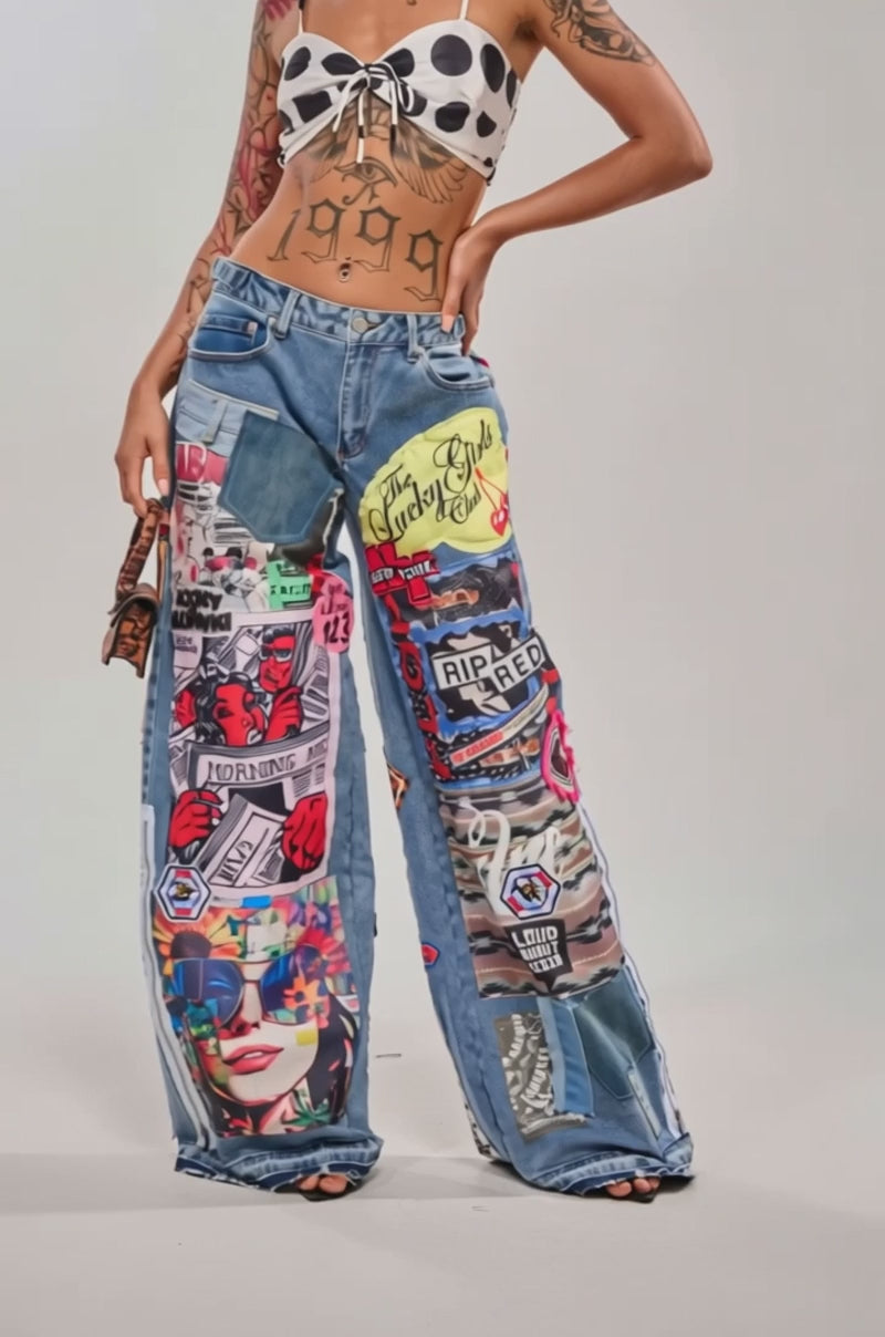 A video of a woman wearing the COOL VERY OVERSIZED DENIM jeans featuring colorful graphic patches, paired with a polka-dot crop top and gold hoop earrings.