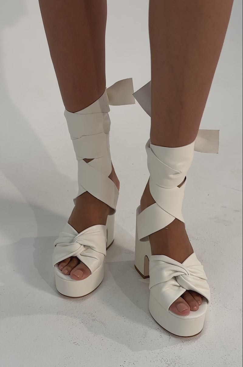 A video of woman wearing AZALEA WANG SAKI WHITE PU CHUNKY WRAP UP SANDAL.