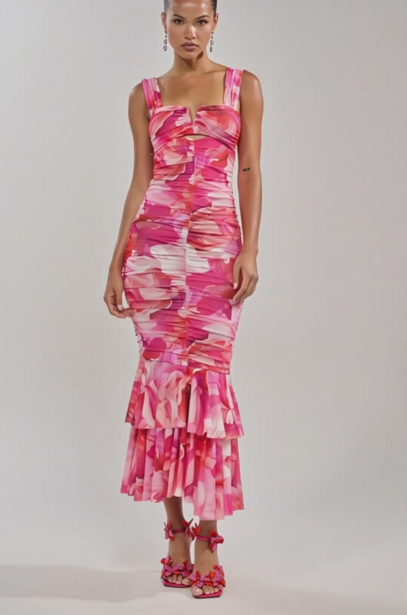 A video of a woman wearing the BODY LANGUAGE MESH MAXI DRESS IN PINK, a fitted sleeveless maxi dress with an abstract floral print and ruffle hem, paired with matching floral heels.
