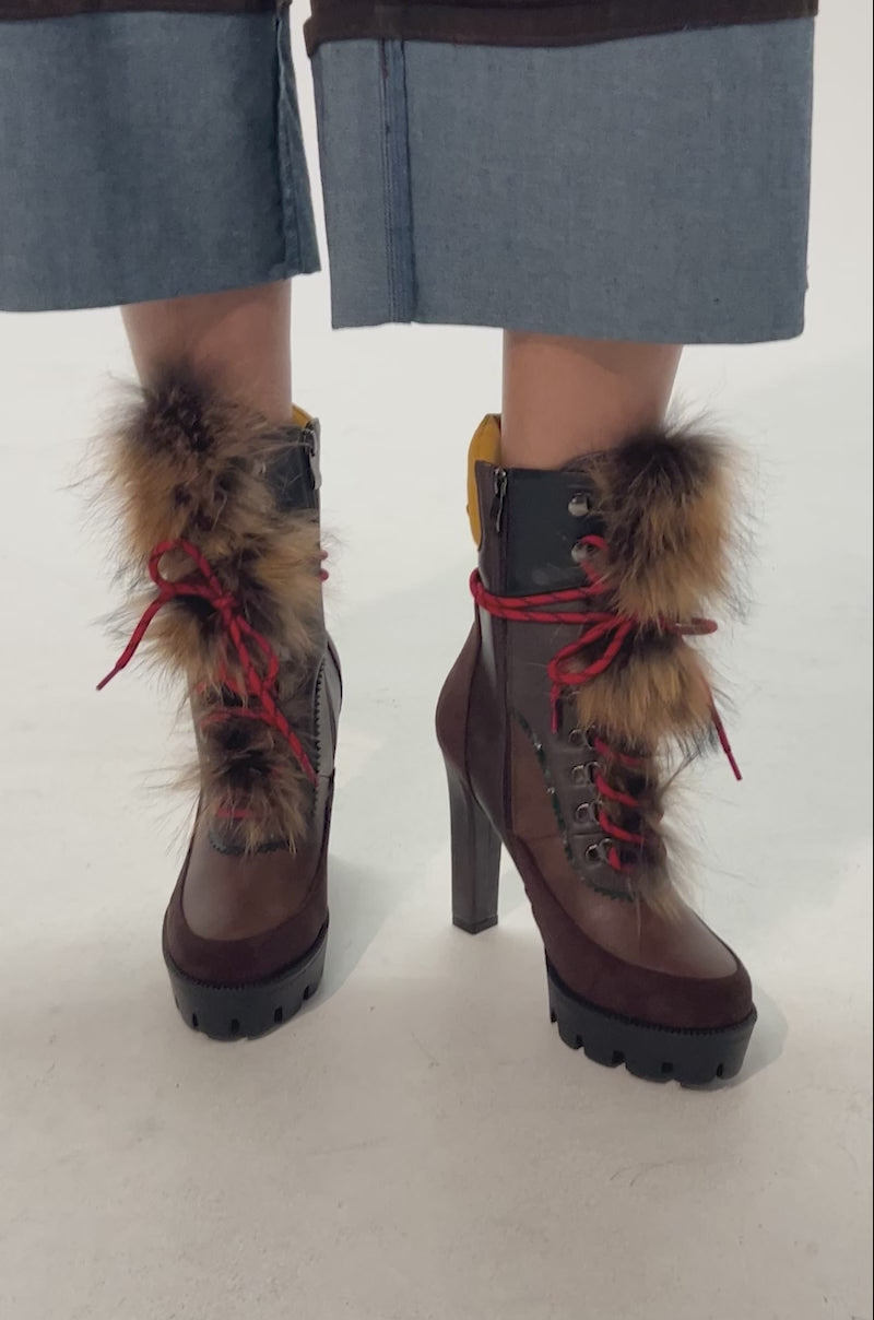 Video of woman modeling the AKIRA GOLD SNUG BROWN MULTI FUR COMBAT BLOCK HEEL boots with red laces and fur trim, paired with cropped pants and denim cuffs