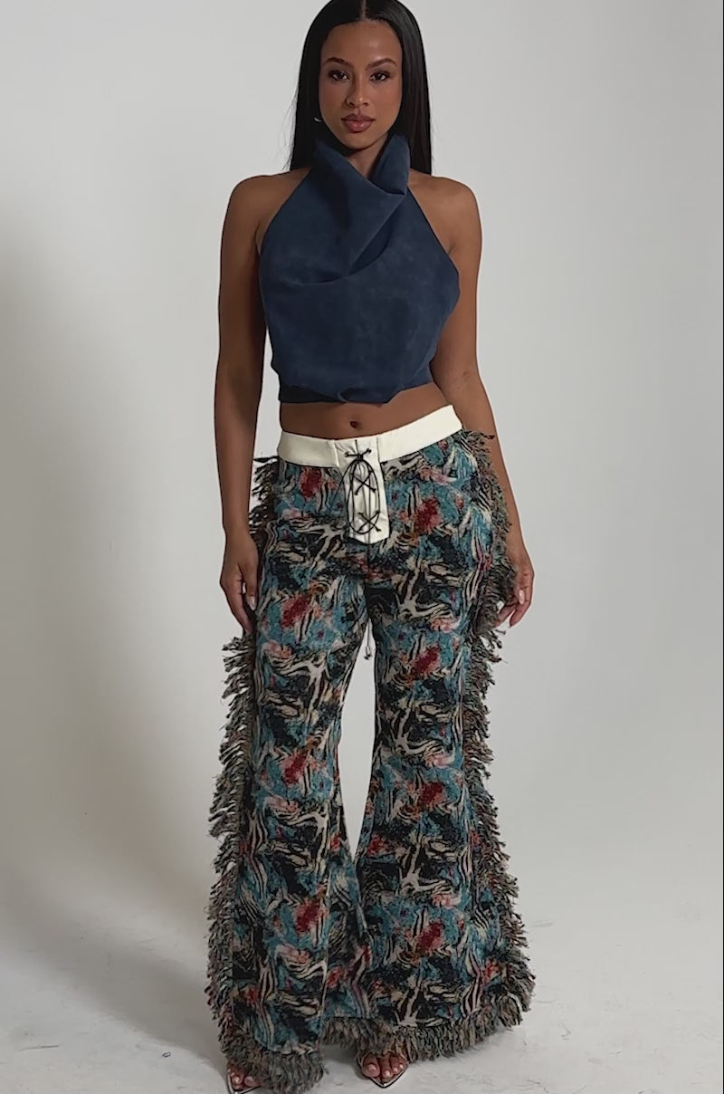 A video of a woman wearing the JANE SUEDE HALTER TOP in navy and colorful high-waisted, wide-leg fringe pants. 