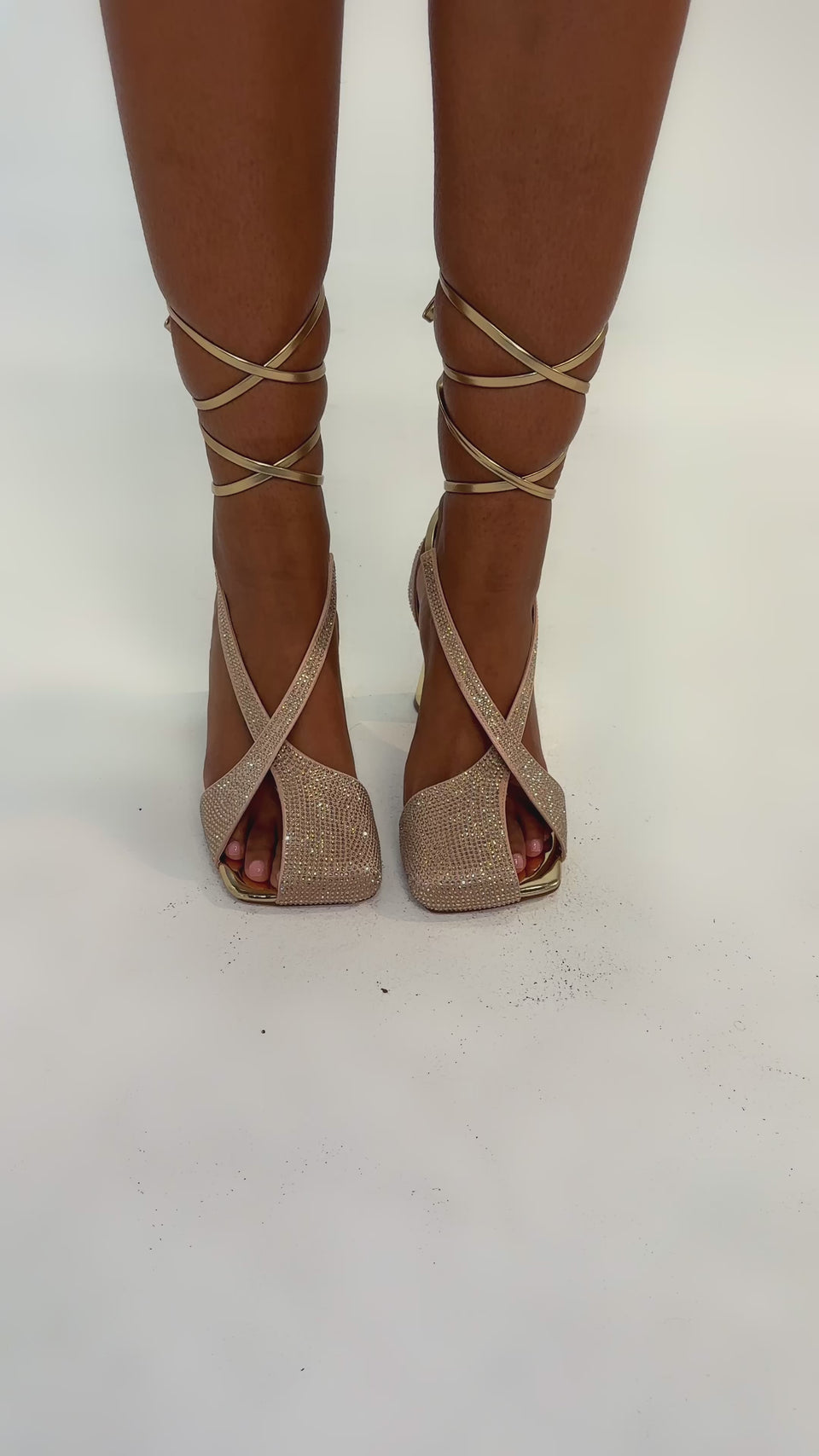 Video of woman modeling the AZALEA WANG BUILANY GOLD RHINESTONE CHUNKY PUMP with sparkly criss-cross straps and thick metallic gold heels