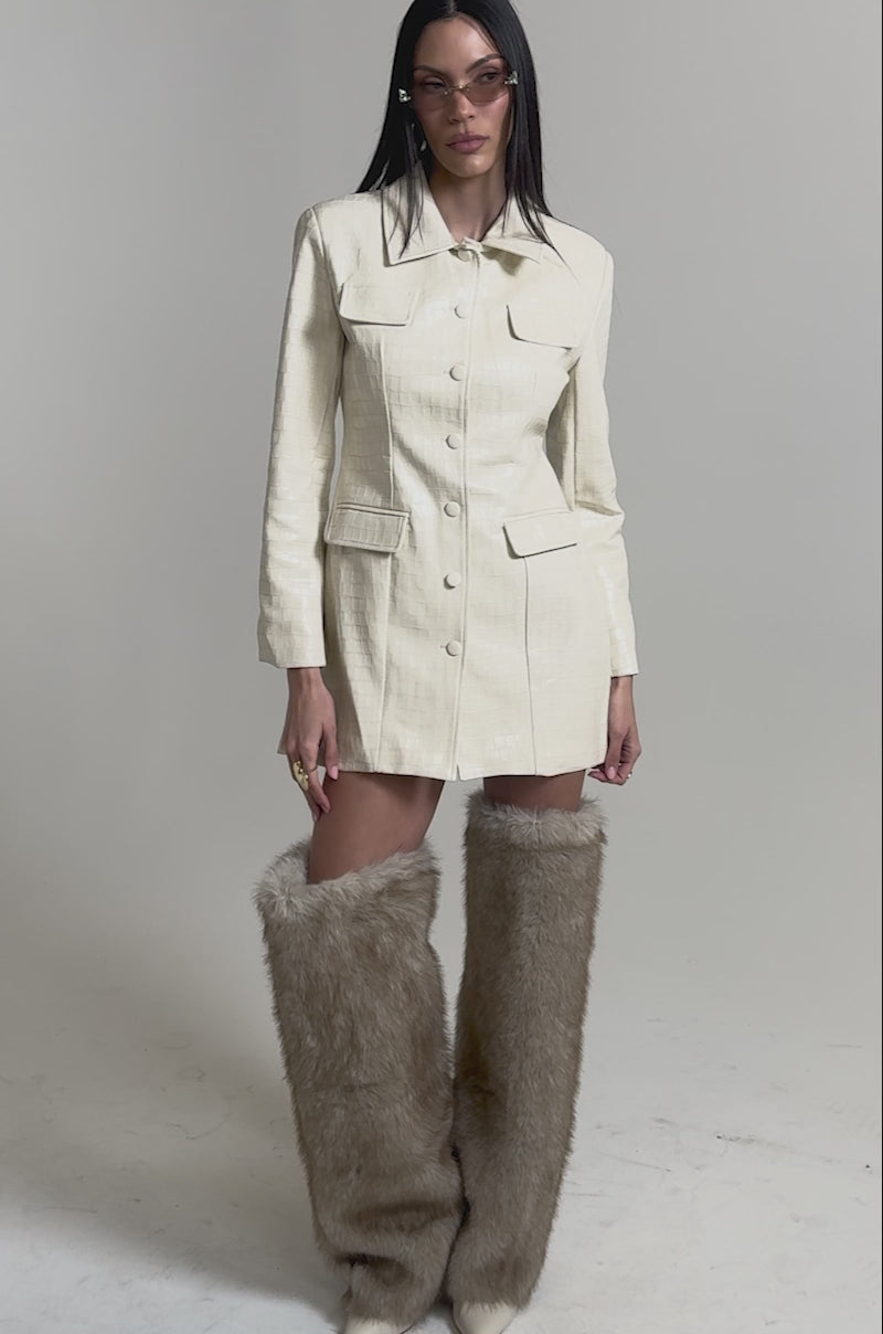 A video of a woman wearing the STANDING ON BUSINESS PU MINI DRESS, styled as an ivory, shiny coat.