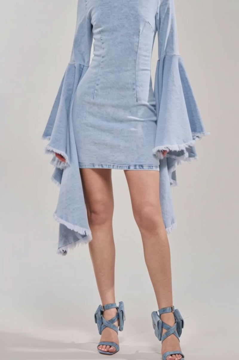 Video of woman modeling the DAYDREAMER DENIM MINI DRESS with dramatic, oversized bell sleeves and matching denim high-heeled sandals 
