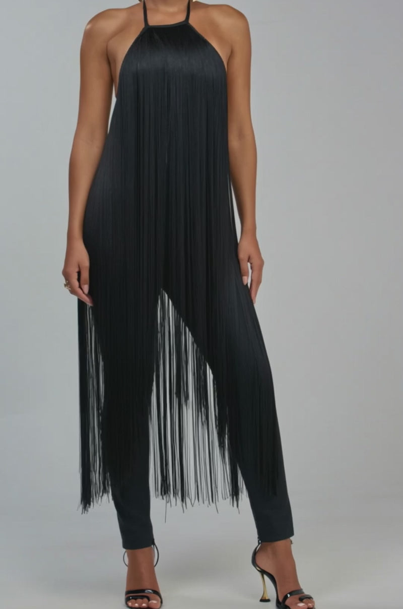 Video of a woman modeling the MAKE A STATEMENT FRINGE JUMPSUIT IN BLACK, with its sleeveless halter style and dynamic fringes.