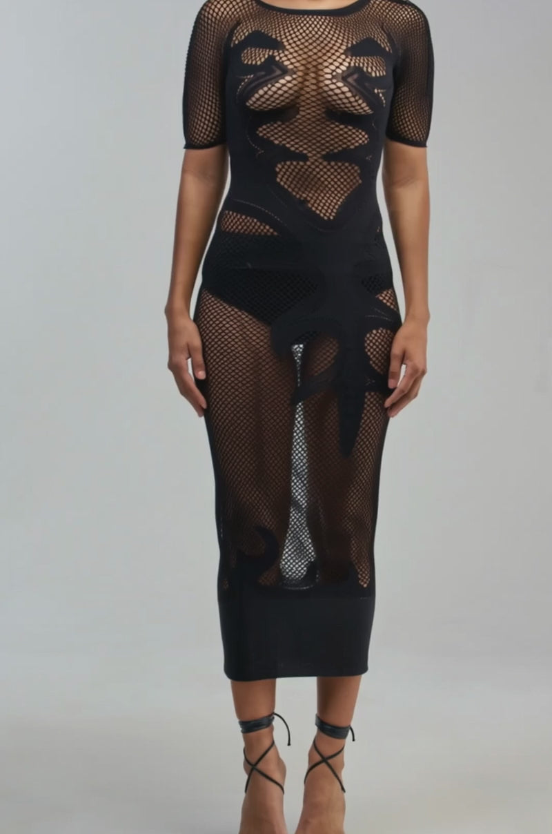 Video of a woman modeling the CLUB HOPPER SUPER STRETCH BODYCON MAXI IN BLACK—a sexy night-out dress featuring bold abstract patterns on sheer black mesh. 