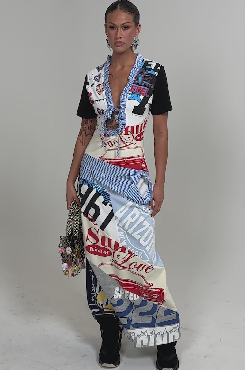 Video of woman modeling the SOMETHING DIFFERENT MAXI DRESS, featuring a vibrant collage print with mixed designs and text. She carries a chain strap bag with keychains and pairs the look with black sneakers against a plain white background.
