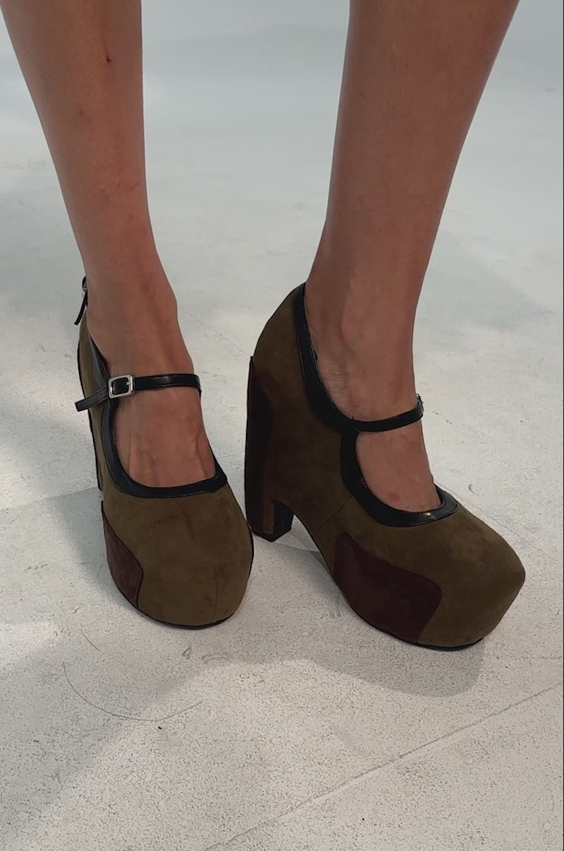 Video of woman modeling the AZALEA WANG LYTHA OLIVEMARY JANE PUMP—olive suede platform heels with black trim, ankle straps, and dark brown accents on the toe and heel.