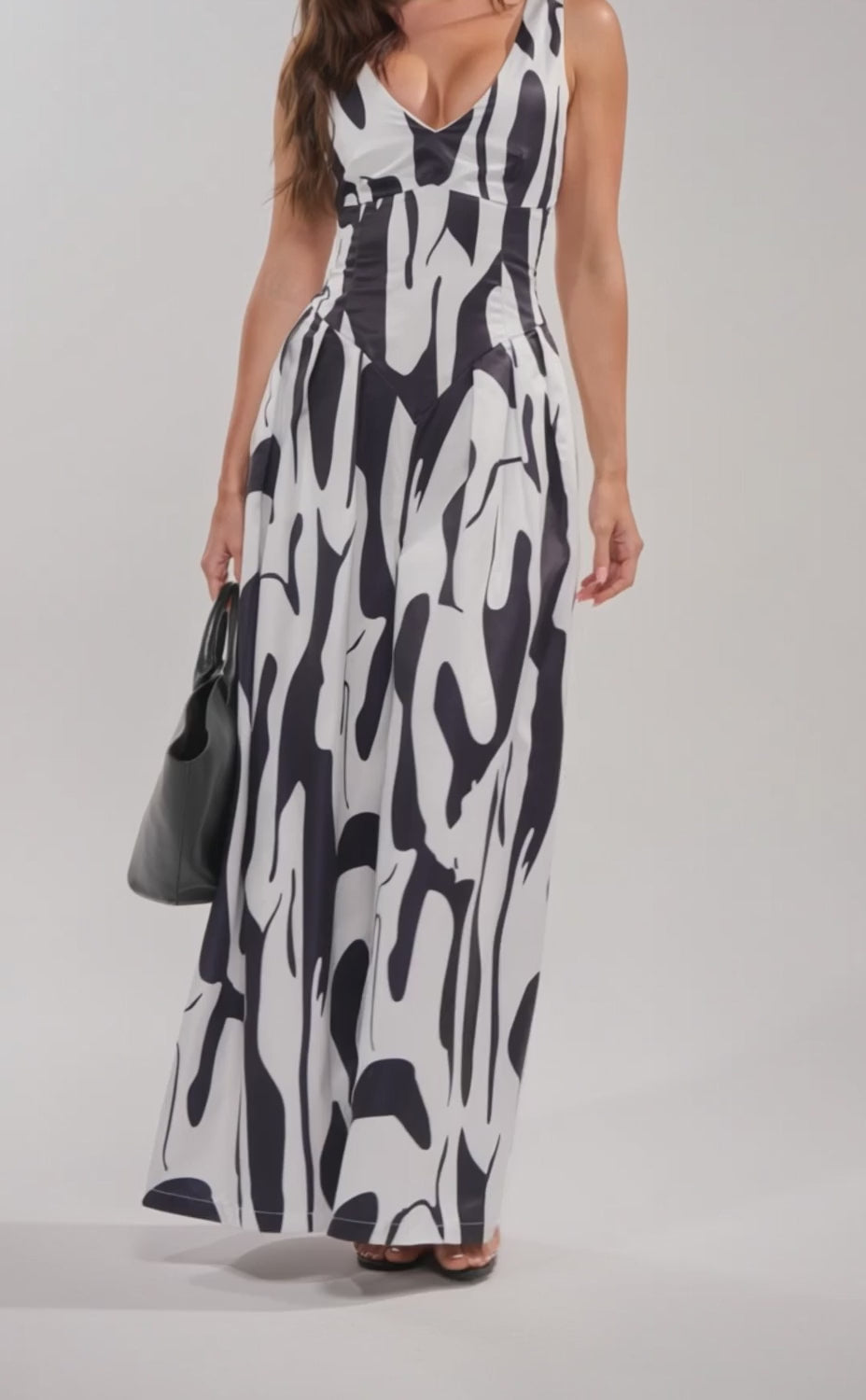 A video of a woman in the READ ALL ABOUT IT POPLIN MAXI DRESS, featuring a black and white abstract print and deep V-neckline. 