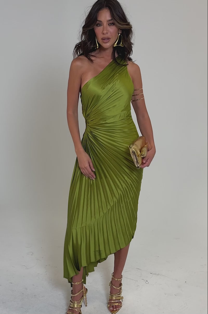 Video of woman modeling the MIDNIGHT MAVEN SLEEVELESS MAXI DRESS IN GREEN, paired with strappy gold heels and a gold clutch, standing confidently against a plain light background.